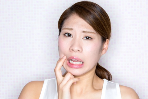 口内炎ができて痛がる女性