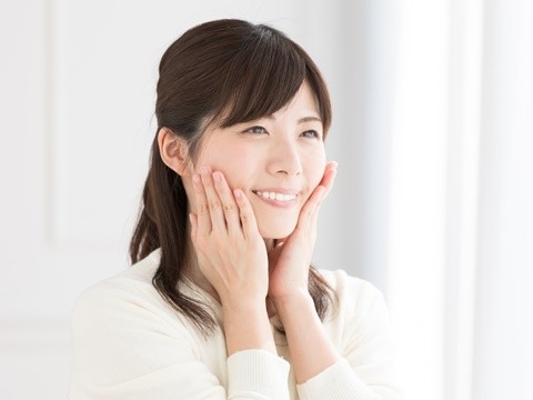 顔に手をあてる笑顔の女性