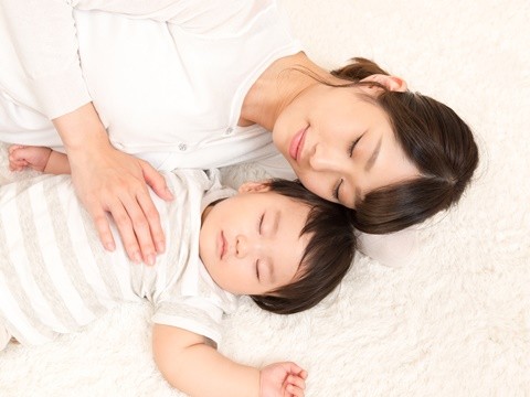 赤ちゃんと添い寝する産後の女性