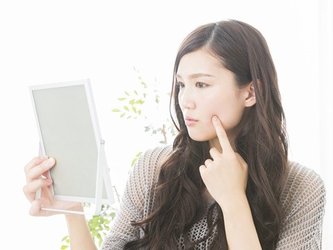 手鏡をみて、口元の乾燥やカサツキを気にしている女性