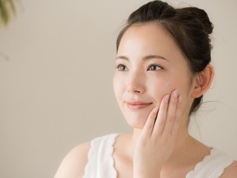 美しい肌に触れる笑顔の女性