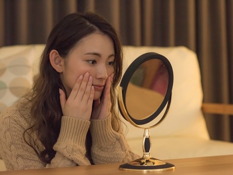 冬になり、肌のハリつやのなさを気にして鏡を覗きこむ女性
