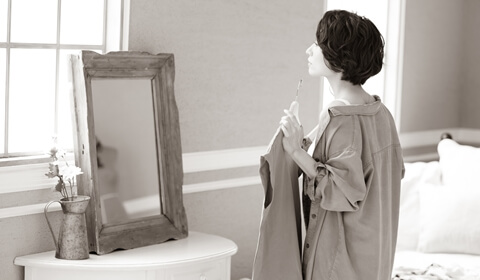 洋服を当てながら鏡を見る40代女性